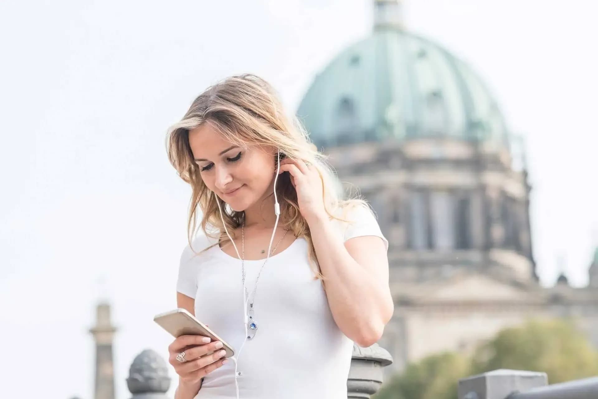 Young visitor listening to an audio guide with headphones next to a monument