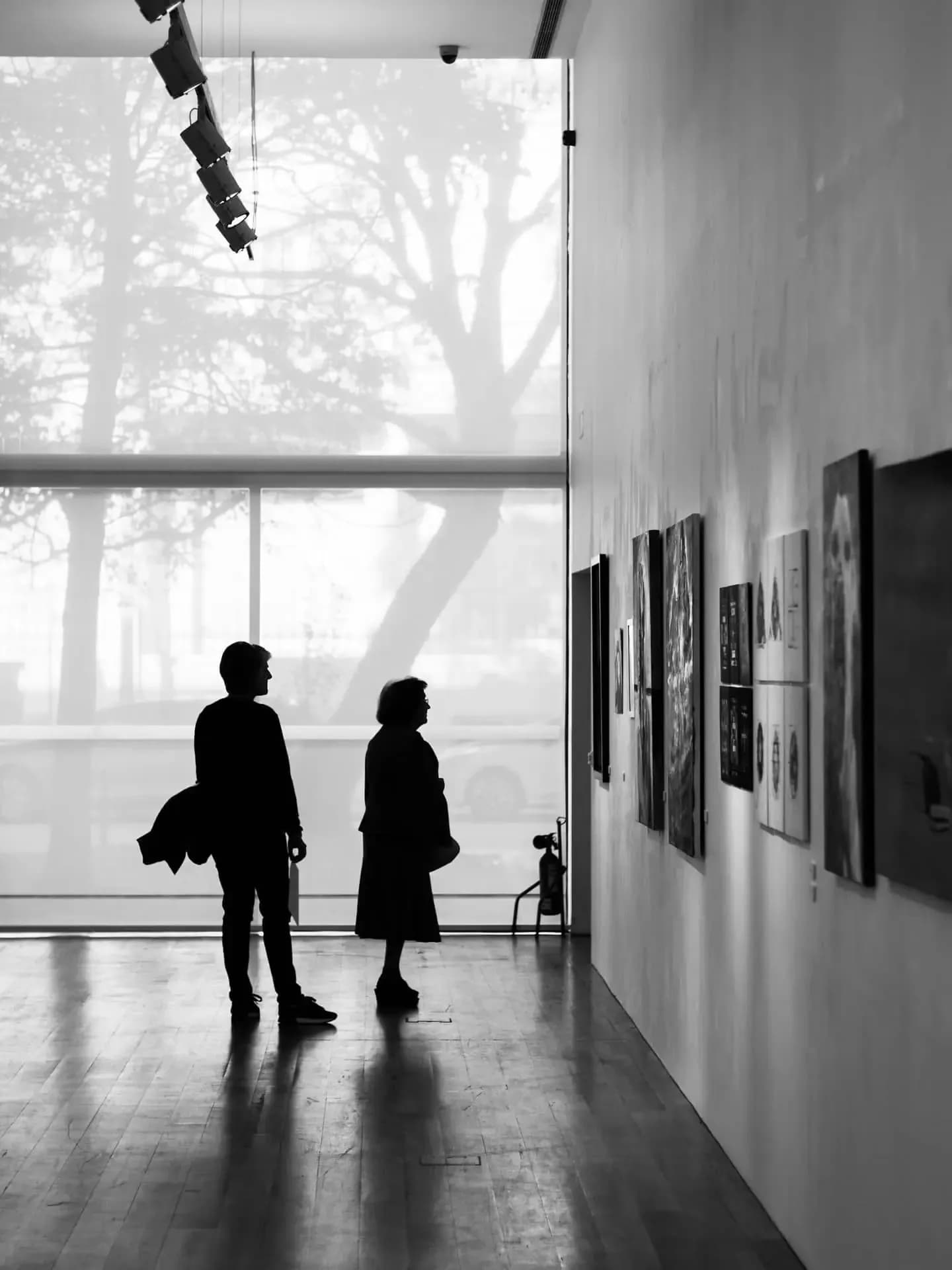 Dos visitantes recorriendo una exposición temporal de pintura