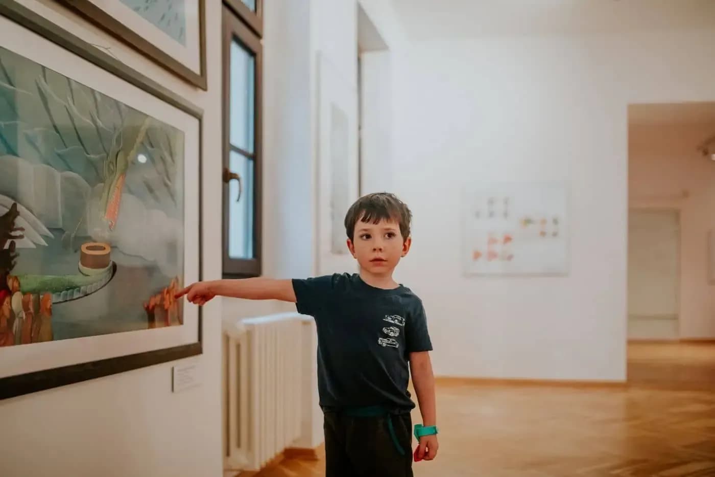 Boy curiously pointing at a framed work in a museum room
