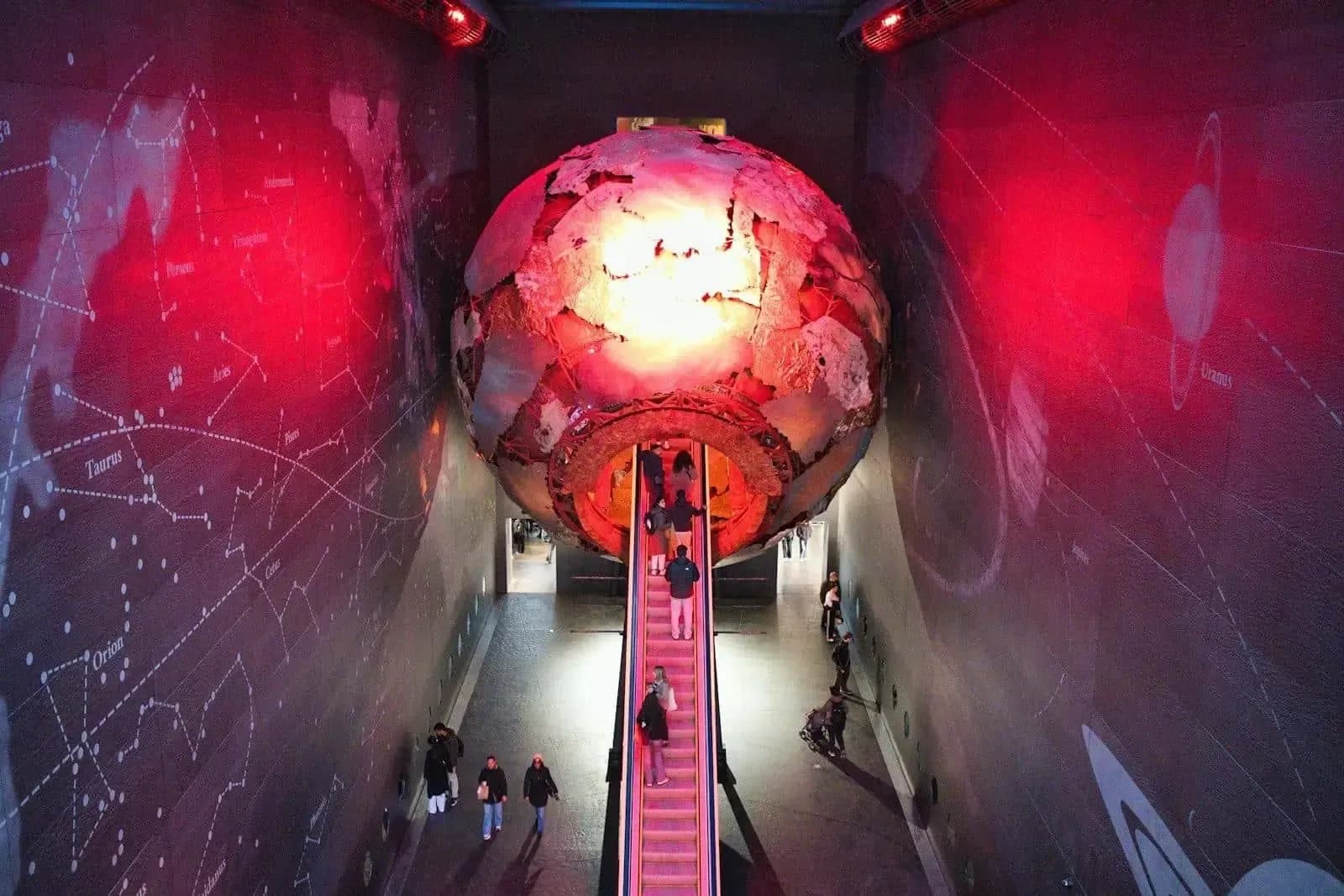 Visitors next to an illuminated globe at the Natural History Museum in London