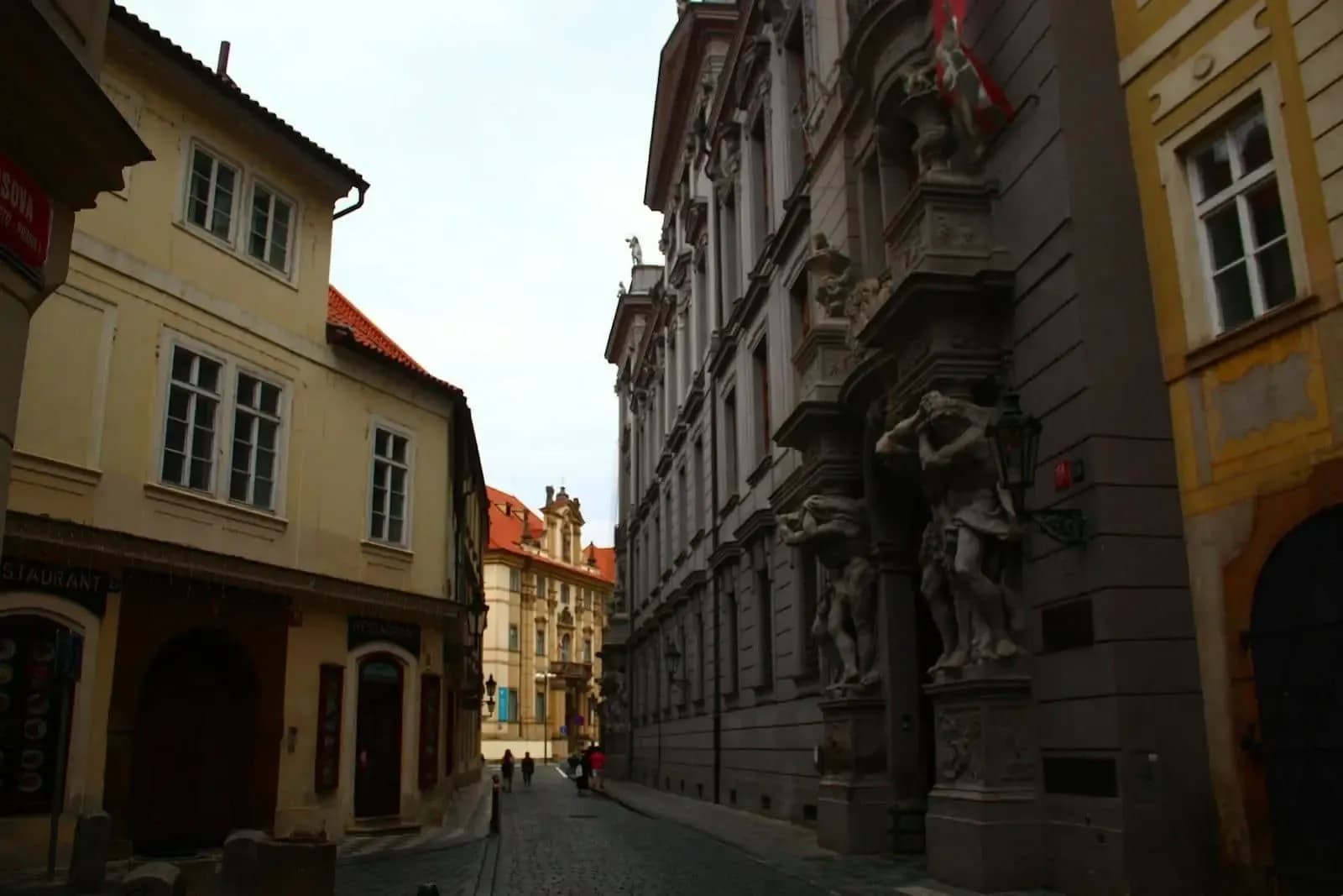 Historic street in central Prague with sculptures and baroque buildings