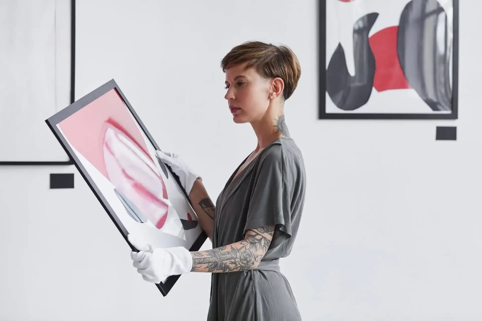 Specialist wearing gloves while handling a framed work in an art gallery
