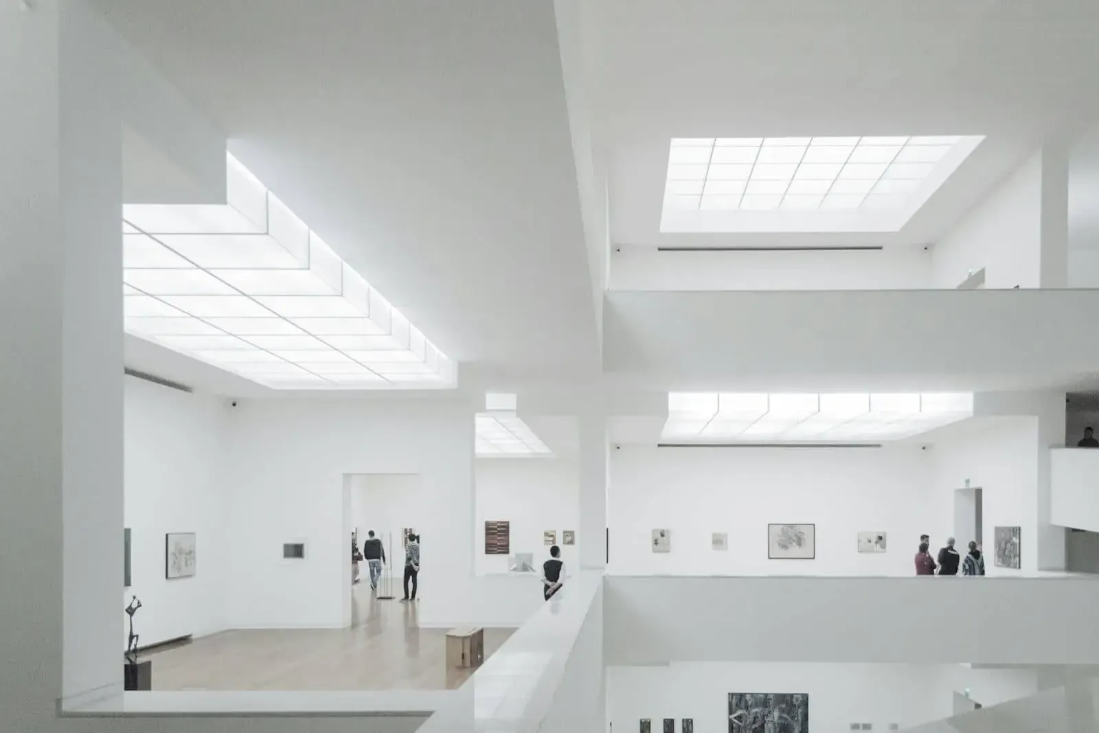 Salas blancas de un museo de arte contemporáneo con obras colgadas y visitantes al fondo