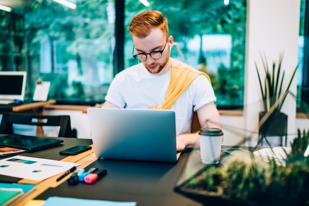 Young guy watching laptop in office space